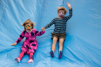 Brother and sister enjoy a slippy slide down the bouncy castle