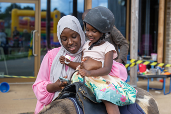 Customer holds her child whilst they enjoy a donkey ride