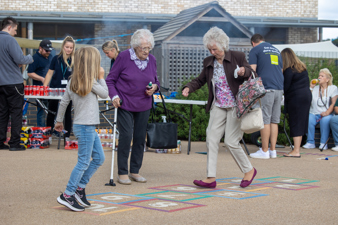 Two elderly residents joyfully play hop-scotch together