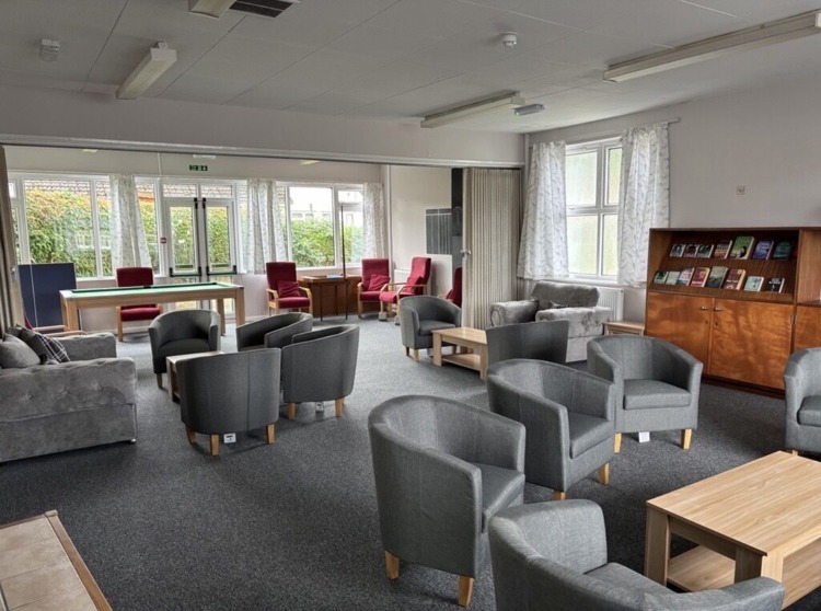 Wick House Community Room after the redesign, bright and airy, new comfy grey chairs, clean white curtains.