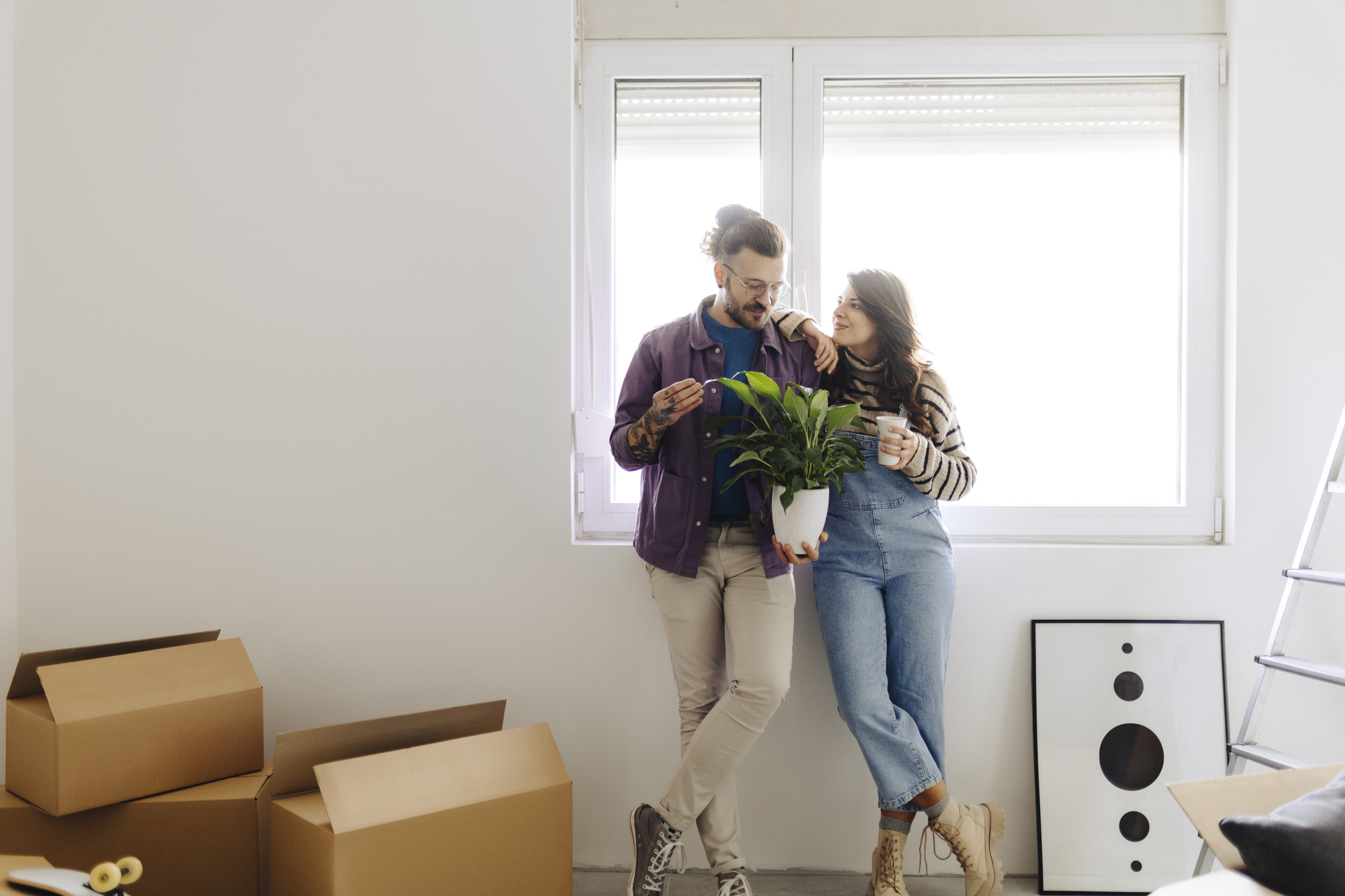 Hetrosexual couple stood by window in flat surrounded by boxes