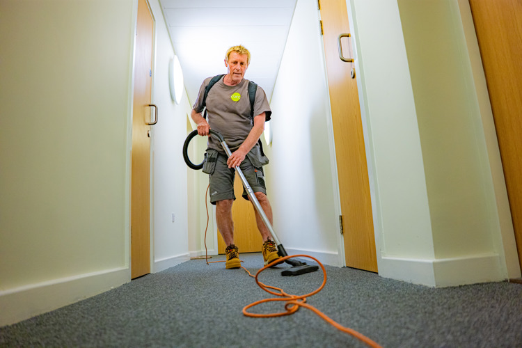 Image of a member of the cleaning team vacuuming a communal area