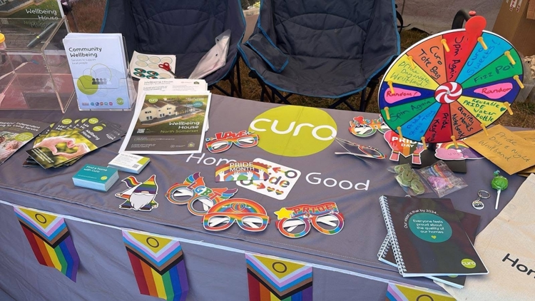 The Curo stand table area, featuring a spin the wheel game, pride props and information on services.
