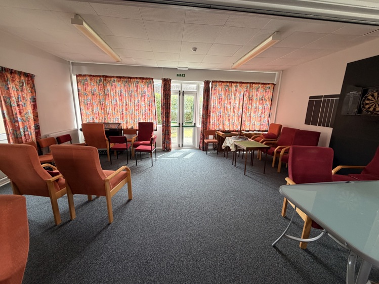 Wick House Community Room before the redesign, dark, old furniture, old red curtains.