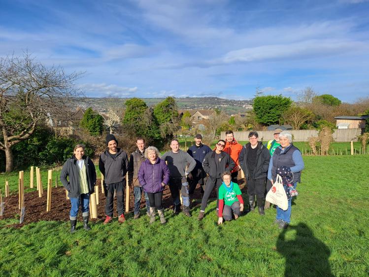 A group of people in front of a patch of newly planted trees
