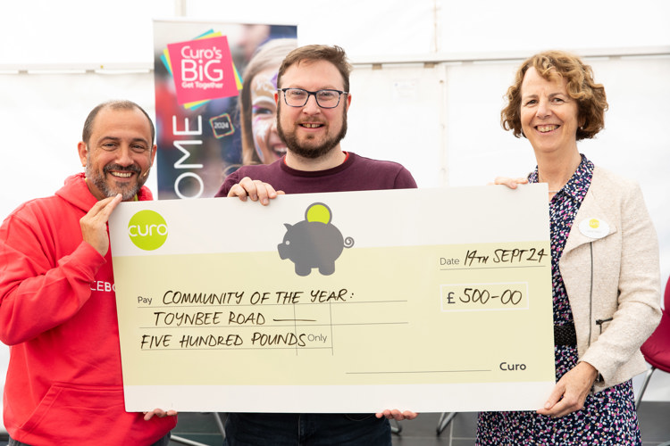 Ian stands with community cheque for £500