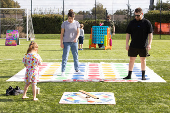 Two parents play giant twister with their toddler