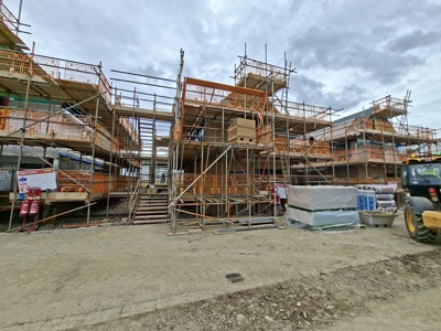 Three two-story buildings covered in scaffolding on busy construction site