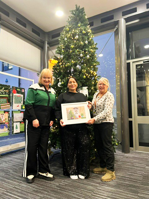 Samantha is presented her framed card design in front of the Curo Christmas tree
